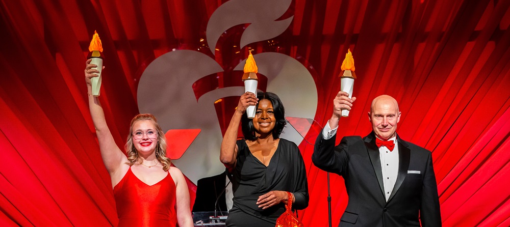Three people on stage holding up lit torches.